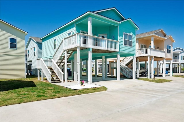 back of property with stairway, a carport, driveway, and a lawn