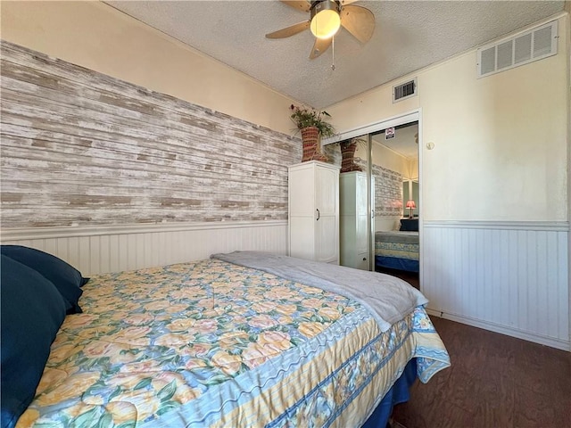 3938 Surfside Unit 3233, Corpus Christi, TX 78402 - bedroom featuring a wainscoted wall, wood finished floors, a closet, a textured ceiling, and ceiling fan
