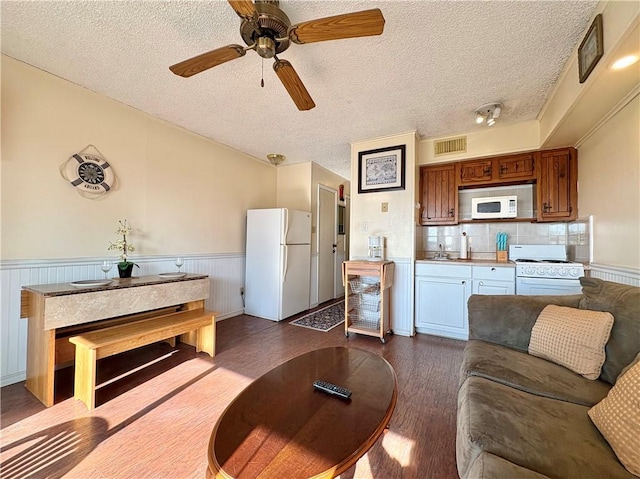 3938 Surfside Unit 3233, Corpus Christi, TX 78402 - living room with dark wood-style floors, wainscoting, a textured ceiling, and a ceiling fan