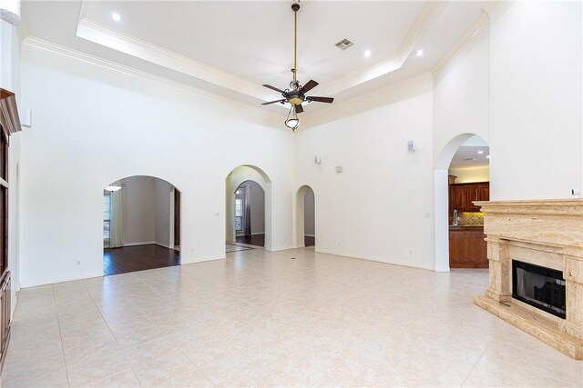 4 E Bar Le Doc Dr, Corpus Christi, TX 78414 - unfurnished living room with ceiling fan, ornamental molding, a high ceiling, a tray ceiling, and a fireplace