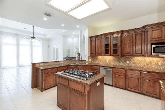 4 E Bar Le Doc Dr, Corpus Christi, TX 78414 - kitchen featuring appliances with stainless steel finishes, a peninsula, tasteful backsplash, dark stone countertops, and a kitchen island