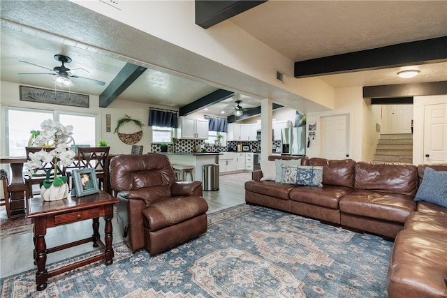 living room with beamed ceiling, wood-type flooring, and ceiling fan