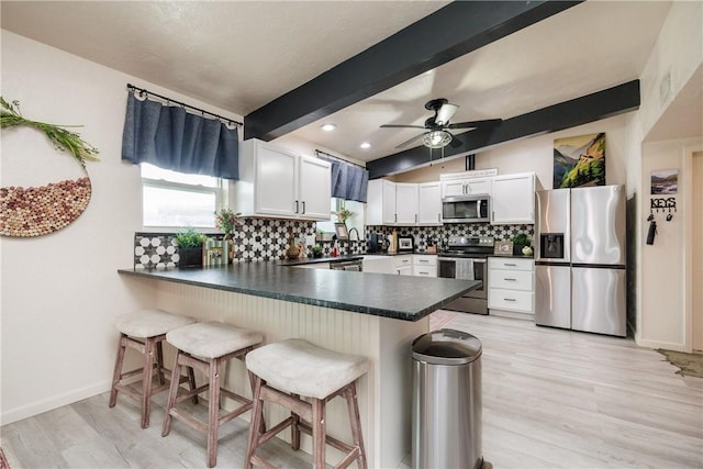 kitchen with white cabinetry, a breakfast bar, stainless steel appliances, and kitchen peninsula