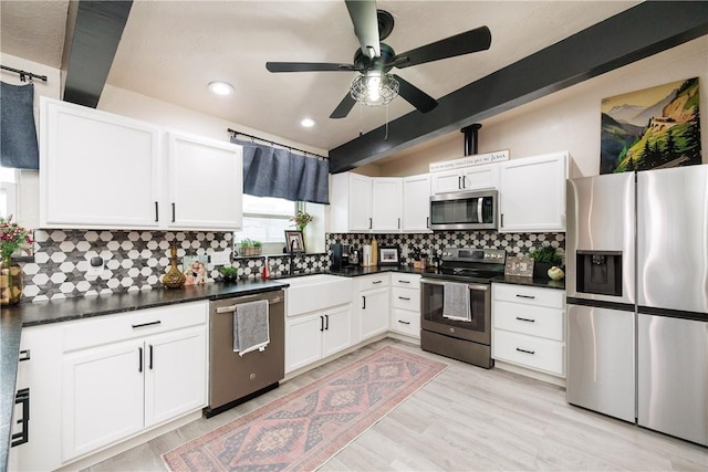 kitchen featuring sink, stainless steel appliances, lofted ceiling with beams, white cabinets, and decorative backsplash