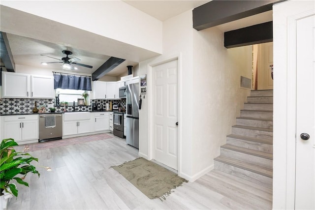 kitchen featuring stainless steel appliances, white cabinets, decorative backsplash, and beamed ceiling