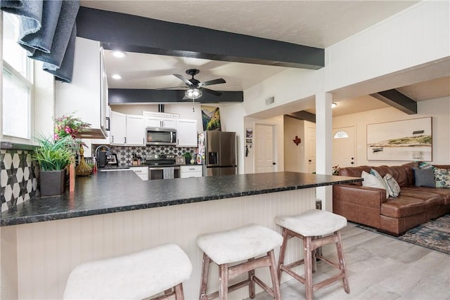 kitchen featuring a breakfast bar, white cabinetry, backsplash, kitchen peninsula, and stainless steel appliances