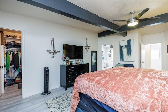 bedroom featuring a walk in closet, beam ceiling, a closet, and light hardwood / wood-style flooring