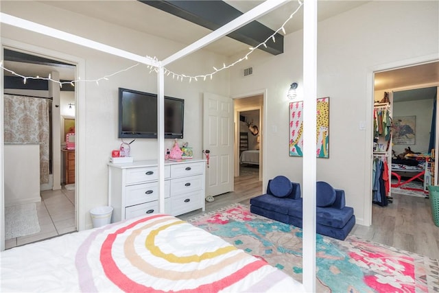 bedroom featuring a closet, a spacious closet, light wood-type flooring, and ensuite bath