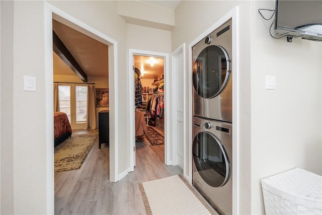 washroom with stacked washer and clothes dryer and light hardwood / wood-style floors