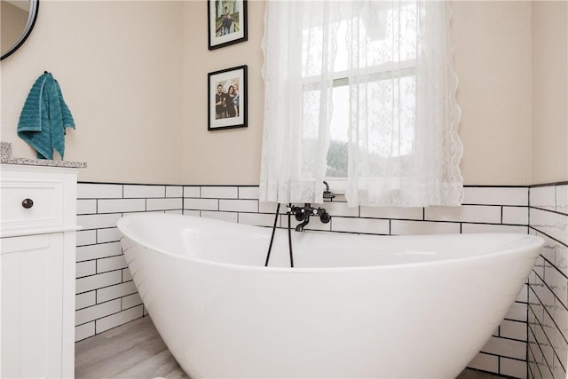 bathroom featuring a bath, hardwood / wood-style floors, and tile walls