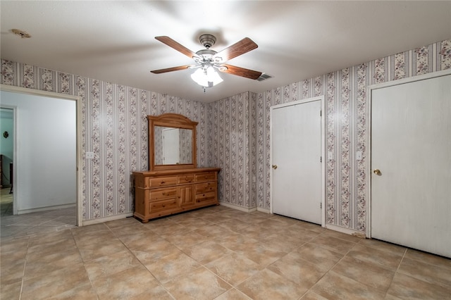 unfurnished bedroom with multiple closets and ceiling fan