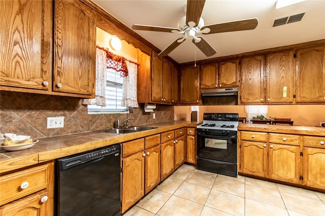 kitchen with sink, black appliances, ceiling fan, light tile patterned floors, and tile counters