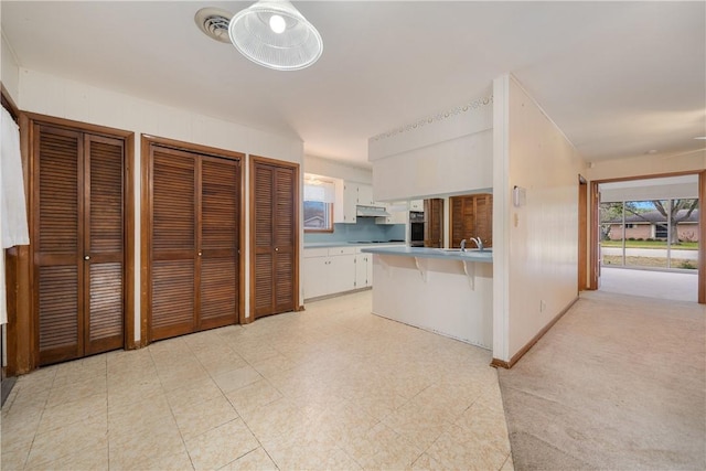 kitchen with sink, stainless steel oven, a kitchen breakfast bar, kitchen peninsula, and white cabinets