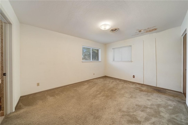 unfurnished bedroom with light colored carpet and a textured ceiling