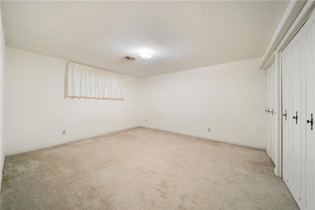 interior space with light colored carpet, a closet, and a textured ceiling