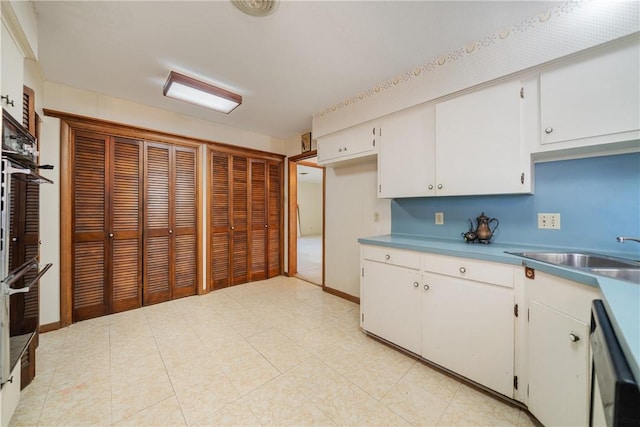 kitchen featuring white cabinetry, sink, white dishwasher, and double oven