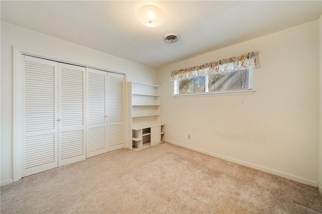 unfurnished bedroom with a closet and light carpet