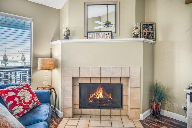 living area with a tile fireplace, light tile patterned floors, and ceiling fan