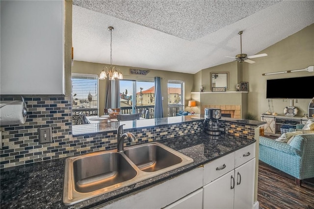 kitchen featuring a textured ceiling, white cabinets, decorative backsplash, sink, and vaulted ceiling