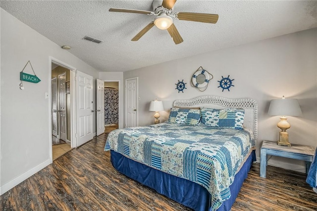 bedroom with dark wood-type flooring, a textured ceiling, and ceiling fan