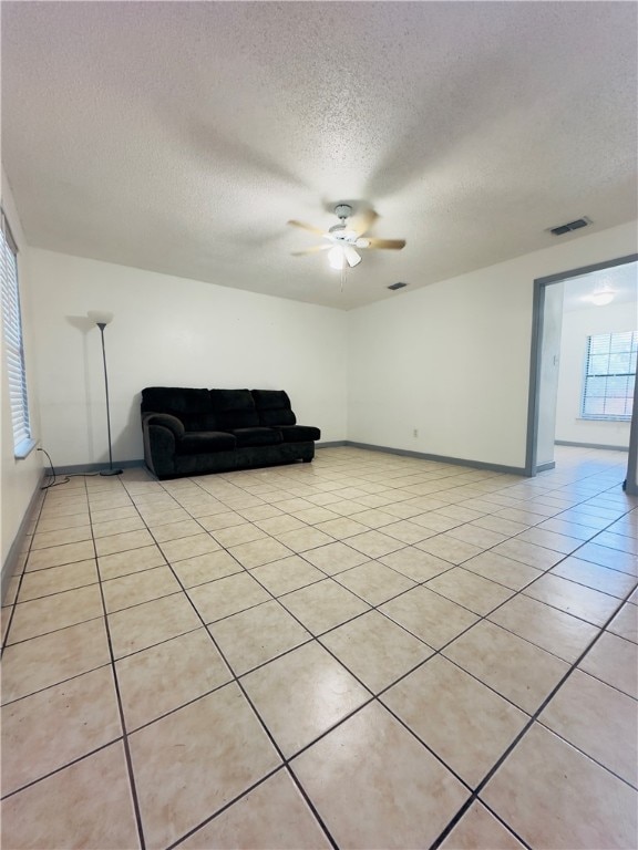 unfurnished living room featuring ceiling fan, a textured ceiling, and light tile patterned floors