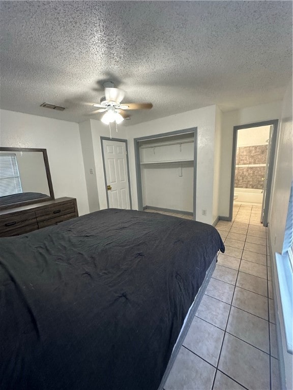 bedroom with ceiling fan, a textured ceiling, light tile patterned floors, and a closet