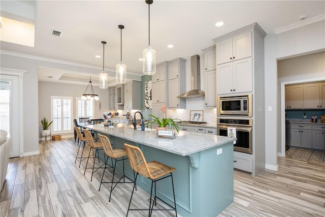 6401 Kobe Dr, Corpus Christi, TX 78414 - kitchen with stainless steel appliances, wall chimney exhaust hood, gray cabinets, backsplash, and ornamental molding