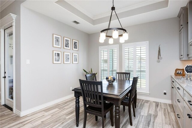 6401 Kobe Dr, Corpus Christi, TX 78414 - dining space featuring a tray ceiling, light wood-type flooring, a chandelier, and ornamental molding