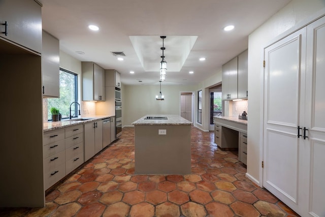 kitchen featuring sink, tasteful backsplash, light stone counters, pendant lighting, and a kitchen island