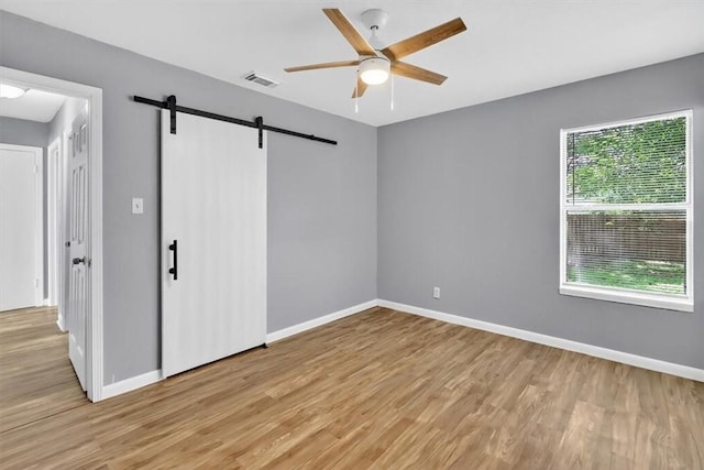 741 Lansdown Dr, Corpus Christi, TX 78412 - unfurnished bedroom with a barn door, light wood finished floors, and ceiling fan