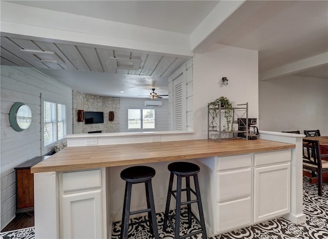 kitchen with wooden counters, a healthy amount of sunlight, and white cabinets