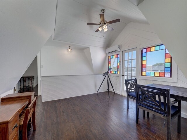 home office featuring a wall unit AC, dark wood-type flooring, vaulted ceiling, wood walls, and ceiling fan