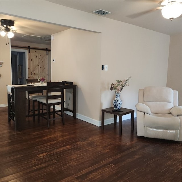 dining space with dark hardwood / wood-style flooring, a barn door, and ceiling fan