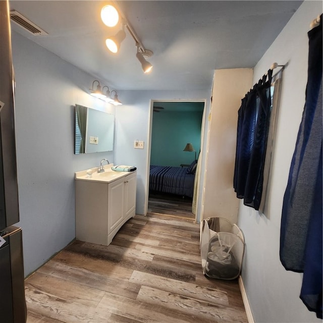 bathroom with hardwood / wood-style floors, vanity, and track lighting