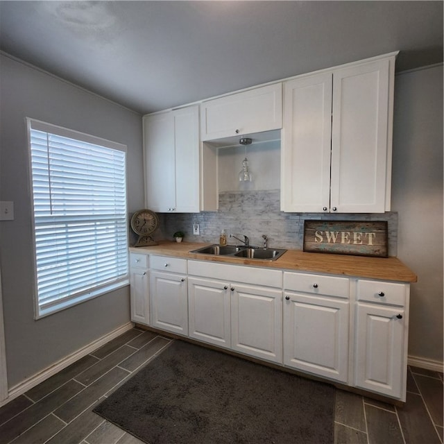 kitchen with wooden counters, dark hardwood / wood-style flooring, white cabinets, sink, and backsplash