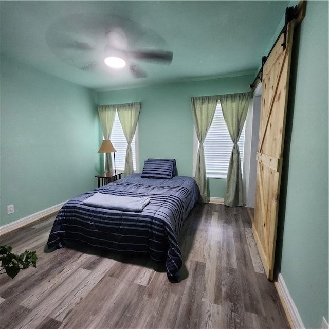 bedroom featuring a barn door, hardwood / wood-style flooring, and ceiling fan