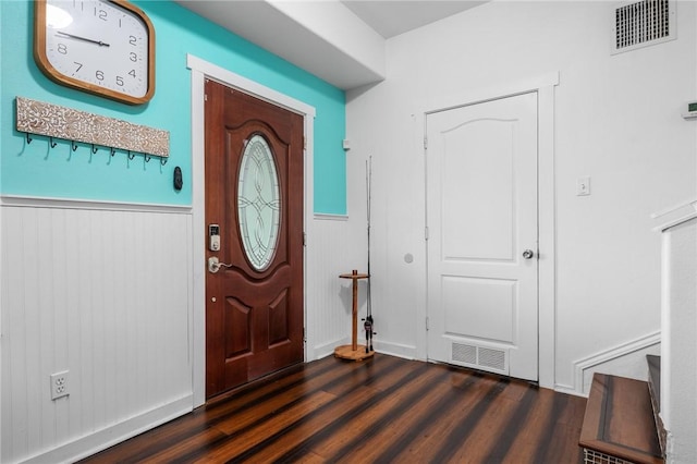 foyer entrance with a wainscoted wall, dark wood-style floors, and visible vents