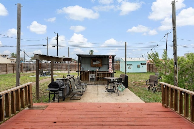 wooden terrace with an outbuilding, a fenced backyard, a grill, a lawn, and a storage unit