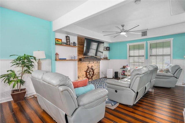 living room featuring a wainscoted wall, ceiling fan, visible vents, and wood finished floors