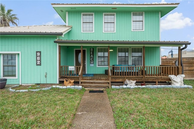 view of front of house with covered porch, metal roof, and a front yard