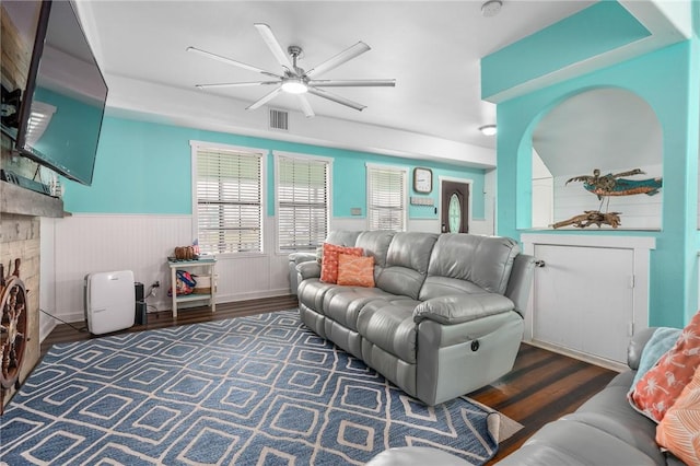 living room featuring a wainscoted wall, a brick fireplace, wood finished floors, and visible vents