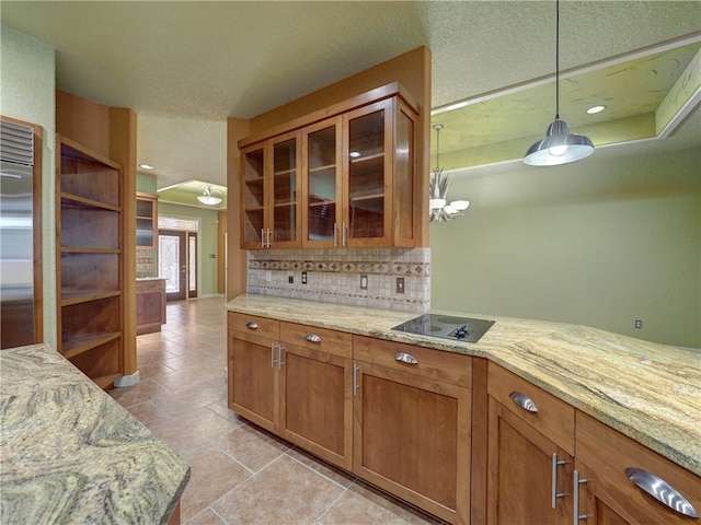 kitchen featuring hanging light fixtures, decorative backsplash, and light stone counters