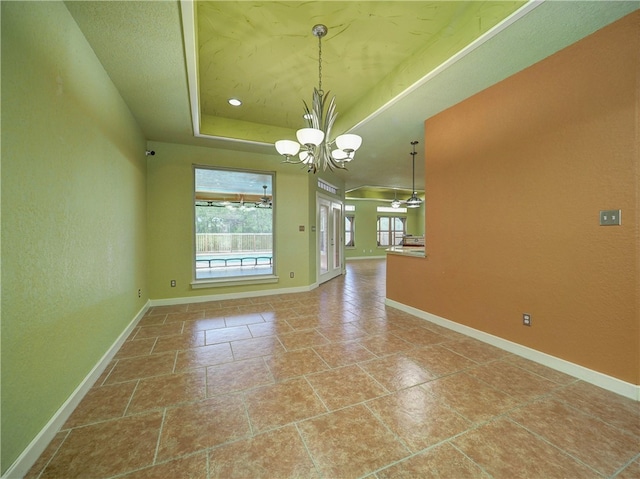 interior space featuring ceiling fan with notable chandelier, tile patterned floors, and a raised ceiling