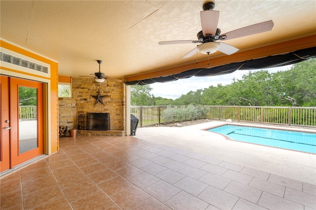 view of swimming pool with an outdoor stone fireplace, ceiling fan, and a patio area