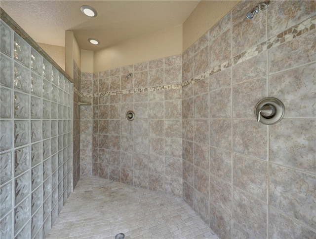 bathroom with a textured ceiling and a tile shower