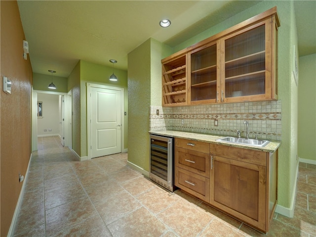 bar featuring backsplash, beverage cooler, sink, and decorative light fixtures