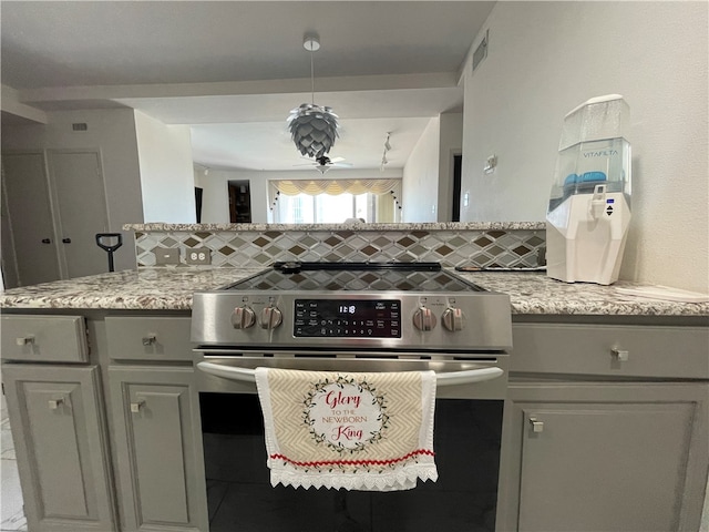 kitchen featuring gray cabinets, light stone countertops, tasteful backsplash, and stainless steel range oven