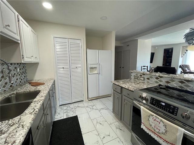 kitchen featuring white cabinetry, sink, gray cabinetry, white refrigerator with ice dispenser, and stainless steel stove