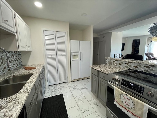 520 S Chaparral St Unit 402, Corpus Christi, TX 78401 - kitchen with white fridge with ice dispenser, stainless steel range with electric stovetop, light marble finish floors, a sink, and light stone countertops