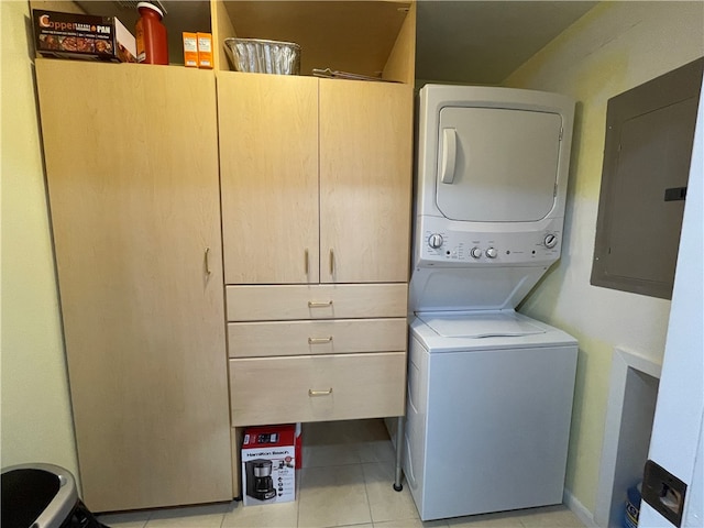 clothes washing area with electric panel, cabinets, light tile patterned floors, and stacked washer / drying machine